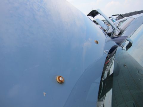 2001 Ford Crown Victoria - A close-up of a blue car's hood shows two amber lights and reflections of other vehicles in the background.