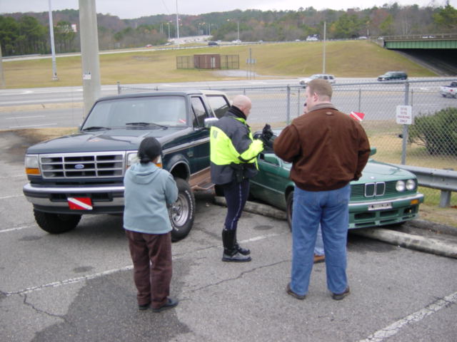 Dark green Ford Bronco parked next to a green BMW that is partially on a curb