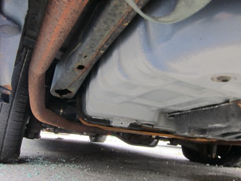 2001 Ford Crown Victoria - Underside of a car, focusing on the exhaust system and fuel tank, with a tire visible.