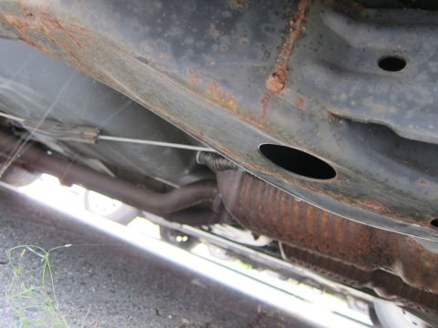 2001 Ford Crown Victoria - The underside of a vehicle shows extensive rust on the frame and exhaust components, indicating poor condition.