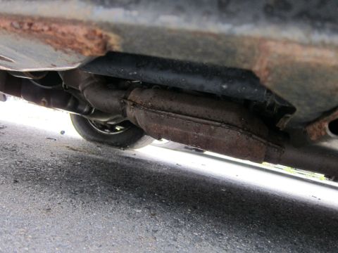 2001 Ford Crown Victoria - The underbody exhaust system shows significant rust on the frame, with a tire visible in the background.