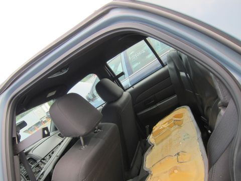2001 Ford Crown Victoria - Interior view of a 2001 Ford Crown Victoria, showing worn seats and a damaged cushion, with another vehicle visible through the rear window.