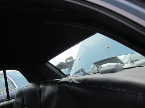 2001 Ford Crown Victoria - View from the back seat of a car, looking out the rear window at other vehicles in a lot.