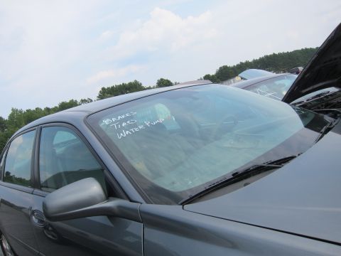2001 Ford Crown Victoria - A car's windshield has handwritten notes about parts, with other vehicles visible in the background.