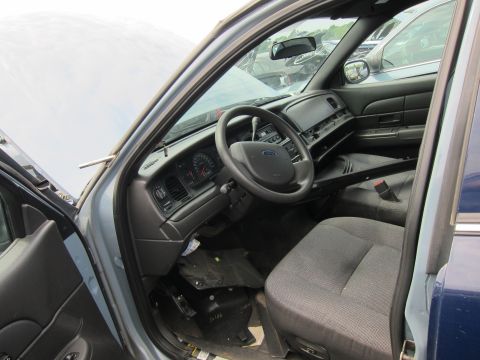 2001 Ford Crown Victoria - The interior of a blue 2001 Ford Crown Victoria police car is visible, with the driver's side door open.