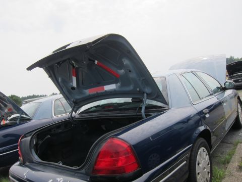 2001 Ford Crown Victoria - Rear view of a dark blue 2001 Ford Crown Victoria, showing the open trunk and hood, with another vehicle visible in the background.