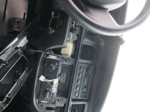 2001 Ford Crown Victoria - The interior of a vehicle shows a disassembled dashboard with exposed wiring and climate control knobs.