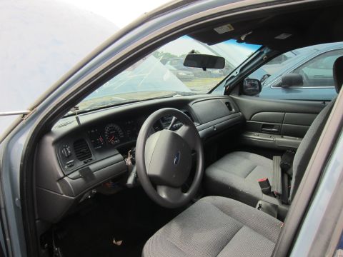 2001 Ford Crown Victoria - Interior view of a 2001 Ford Crown Victoria, showing the driver's side dashboard and seats. Another vehicle is parked nearby.