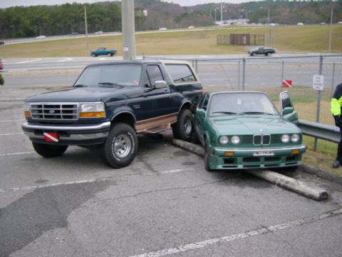 1995 Ford Bronco - A Ford Bronco and a BMW 3 Series are involved in a collision, with the BMW wedged against a concrete barrier.
