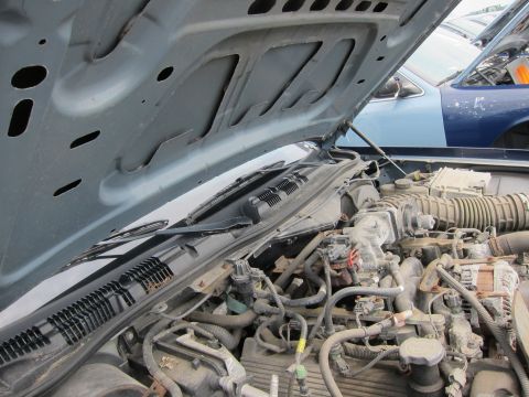 2001 Ford Crown Victoria - The engine bay of a 2001 Ford Crown Victoria is shown with the hood open, revealing dusty mechanical parts.