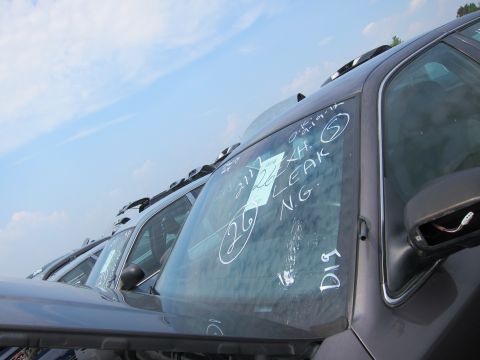 2001 Ford Crown Victoria - Cars are parked in rows at a junkyard, with handwritten notes on the windshields.
