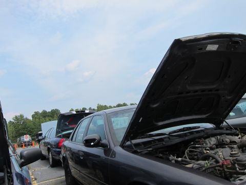 2001 Ford Crown Victoria - Several vehicles are parked in a lot under a cloudy sky, with one Ford Crown Victoria's hood open.