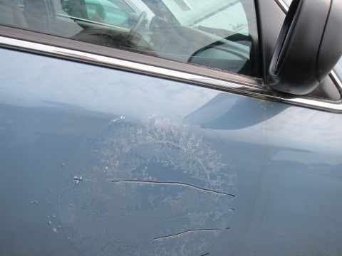 2001 Ford Crown Victoria - The paint on this car door is chipped and scratched, revealing a circular pattern underneath.