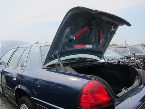 2001 Ford Crown Victoria - View of the trunk and engine bay of a 2001 Ford Crown Victoria, with another vehicle in the background.