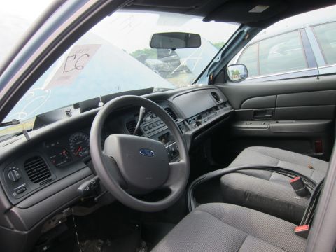 2001 Ford Crown Victoria - The interior of a 2001 Ford Crown Victoria police car, with the dashboard and front seats visible. Another vehicle is seen through the wind…
