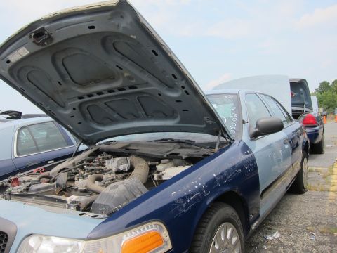 2001 Ford Crown Victoria - A two-tone Ford Crown Victoria sits with its hood open, parked next to another vehicle.