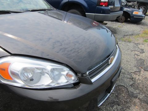 2001 Ford Crown Victoria - Front view of a dark sedan with a chrome grille and Chevrolet emblem, parked in a lot with other vehicles.