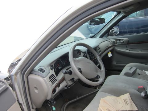 2001 Ford Crown Victoria - The interior of a car is visible, showing the dashboard, steering wheel, and seats. Some papers are scattered on the passenger seat.