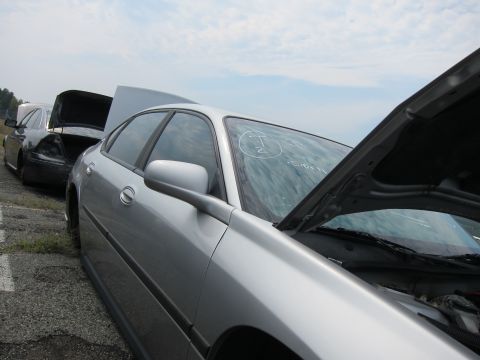 2001 Ford Crown Victoria - Two sedans are parked side-by-side, one with its hood open and the other with visible rear damage.
