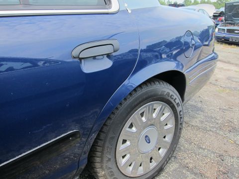 2001 Ford Crown Victoria - A blue sedan is parked outdoors, with other vehicles visible in the background.
