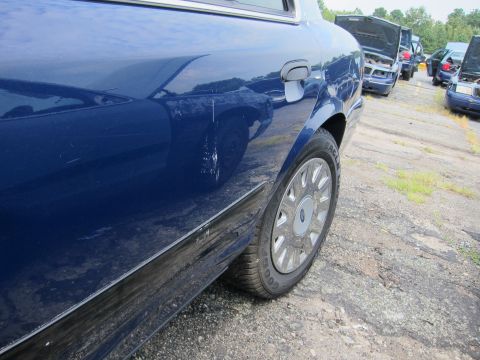 2001 Ford Crown Victoria - A blue 2001 Ford Crown Victoria is parked in a lot with other vehicles.