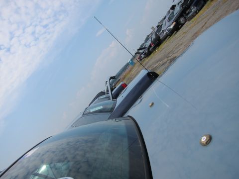 2001 Ford Crown Victoria - A light blue car is parked in a lot with other vehicles visible in the background under a cloudy sky.