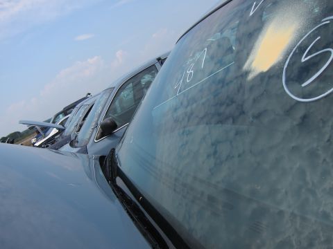 2001 Ford Crown Victoria - Multiple vehicles are parked in a lot under a cloudy sky, with handwritten numbers visible on the windshields.