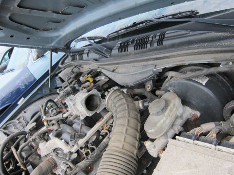 2001 Ford Crown Victoria - Close-up of a vehicle's engine bay, showing various components and another car behind it.