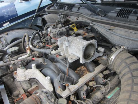 2001 Ford Crown Victoria - A close-up view of a car's engine bay, showing the throttle body and surrounding components.