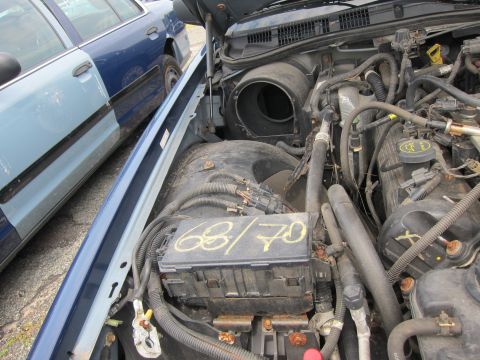 2001 Ford Crown Victoria - The engine bay of a blue car is shown, with a fuse box marked '68/70' and parts of two other car doors.