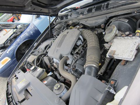 2001 Ford Crown Victoria - The engine compartment of a vehicle is shown, with another car partially visible in the background.
