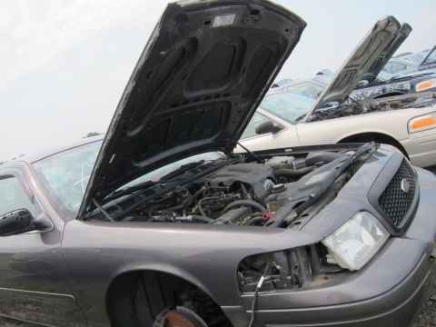 2001 Ford Crown Victoria - The front of a gray Ford Crown Victoria is shown with its hood open, revealing the engine compartment and front grille.