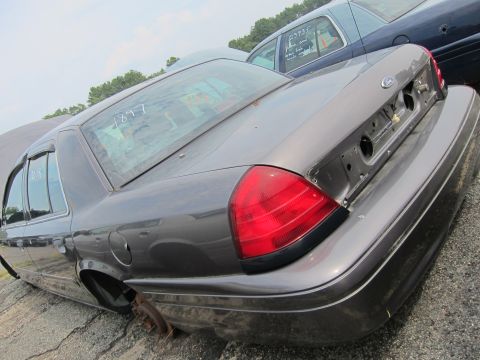 2001 Ford Crown Victoria - Rear view of a gray 2001 Ford Crown Victoria, showing its taillight and missing license plate assembly.