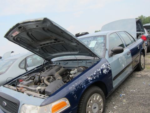 2001 Ford Crown Victoria - Junkyard Ford Crown Victoria, hood and trunk open, flat rear tire visible.