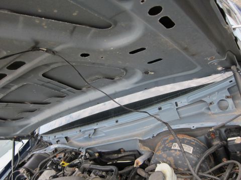 2001 Ford Crown Victoria - The underside of a car's hood is open, revealing the engine compartment and various mechanical parts.