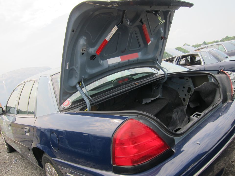 Blue 2001 Ford Crown Victoria with open trunk, rear quarter view, showing damage to the trunk interior