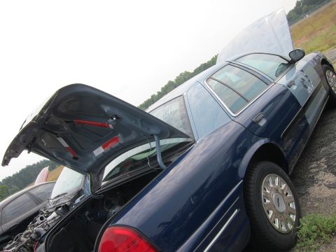 2001 Ford Crown Victoria - A blue 2001 Ford Crown Victoria is shown with both the hood and trunk open, revealing the engine and rear cargo area.