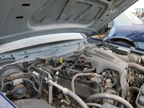 2001 Ford Crown Victoria - The engine bay of a blue 2001 Ford Crown Victoria is visible with the hood raised, revealing the engine and surrounding parts.