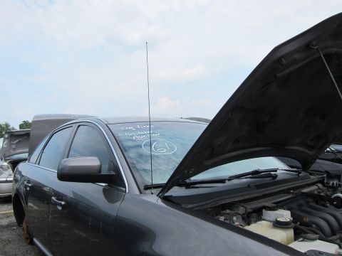 2001 Ford Crown Victoria - A dark sedan sits in a junkyard with its hood open, revealing the engine bay. Text on the windshield indicates it was part of an auction.