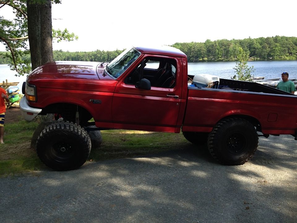 Red 1996 Ford F-150 side view, lifted with large tires
