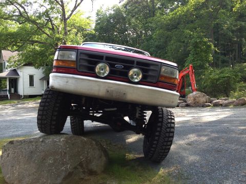1996 Ford F-150 - Red 1996 Ford F-150 with lifted suspension is positioned on rocks.
