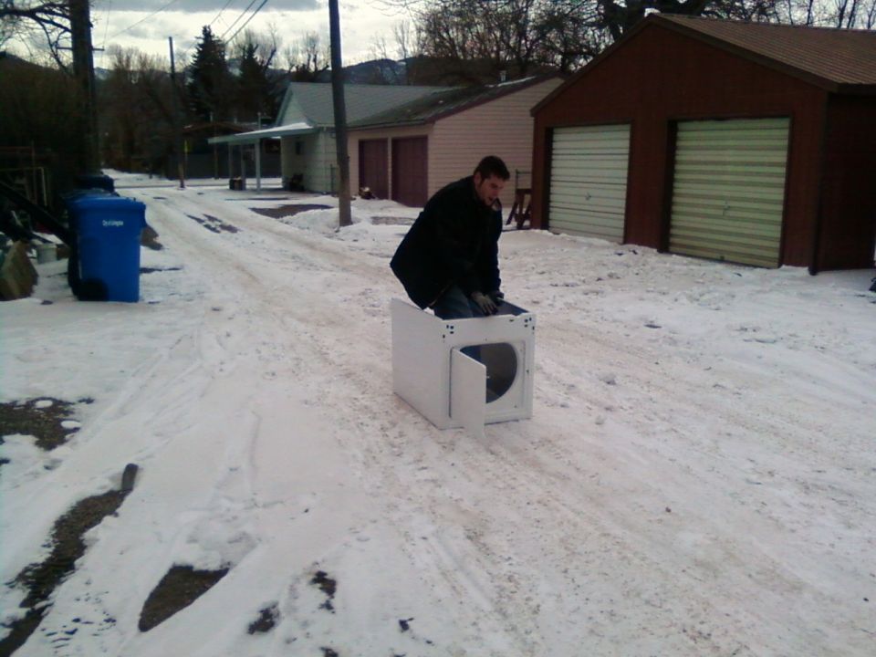 Man sits in a white appliance on a snowy road