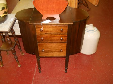 2006 Ford E350 - An antique wooden cabinet with drawers sits on a red floor next to a large jug.