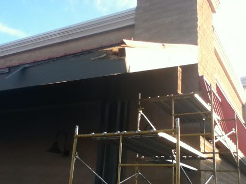 2006 Ford E350 - Construction work is underway on the exterior of a building, with scaffolding set up near the damaged eaves.