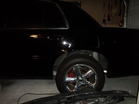 2004 Mercury Grand Marquis - A black sedan is parked indoors, with its rear wheel and chrome rims visible.