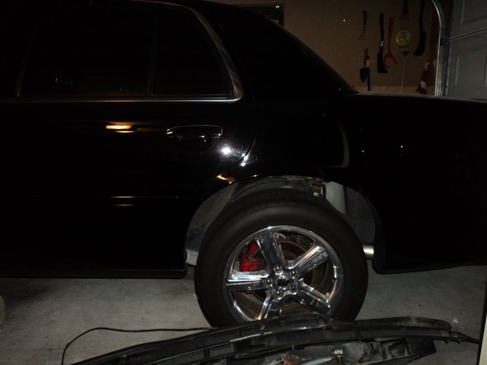 black sedan side view, showing chrome wheels and red brake calipers