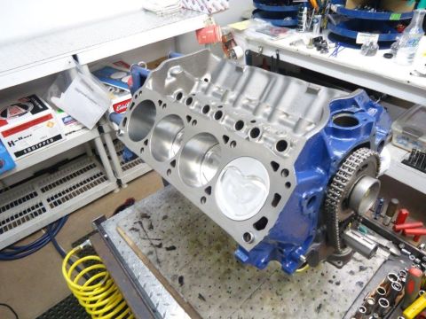 1982 Ford Bronco - A blue engine block with pistons and timing chain is shown on a workbench.