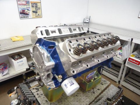 1982 Ford Bronco - A V8 engine block is shown with its components, including valve springs and an oil filter, in a workshop setting.