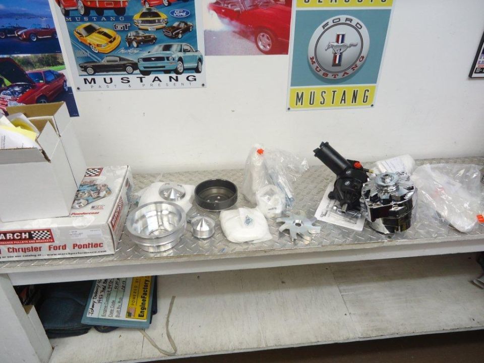 Engine parts including a chrome alternator and power steering pump on a metal shelf