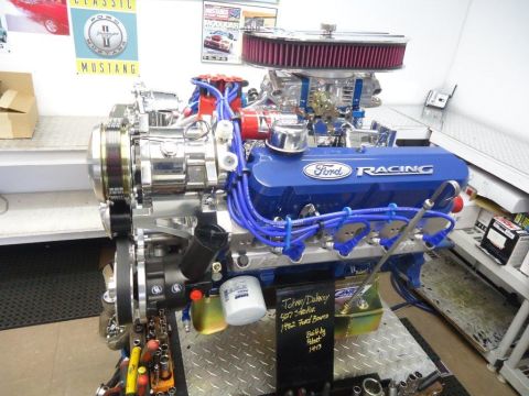 1982 Ford Bronco - A blue Ford Racing V8 engine is displayed on a stand with various tools around it.